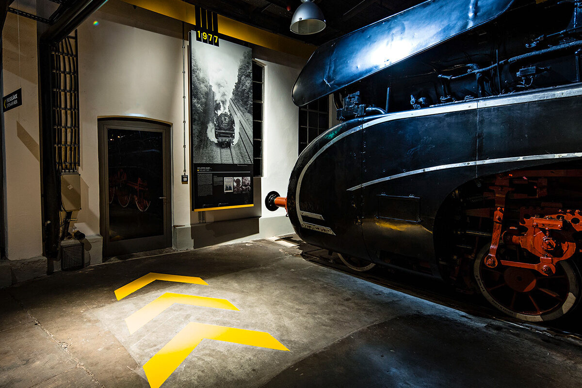 Three yellow arrows show the way through the museum. The steam locomotive 10001 can be seen on the right.