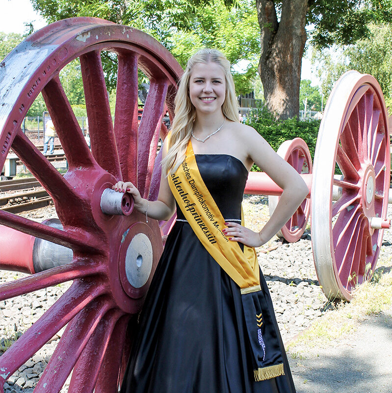 The princess of the coal yard Cara I. is posing with her sash next to a wheel