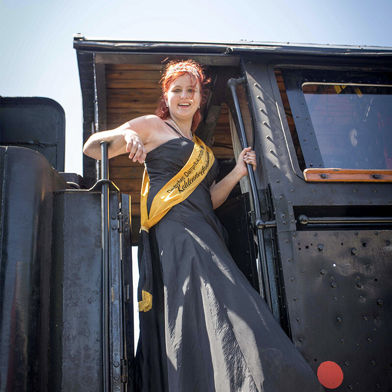 The princess of the coal yard Anja I. is wearing a sash and standing in the door of a locomotive