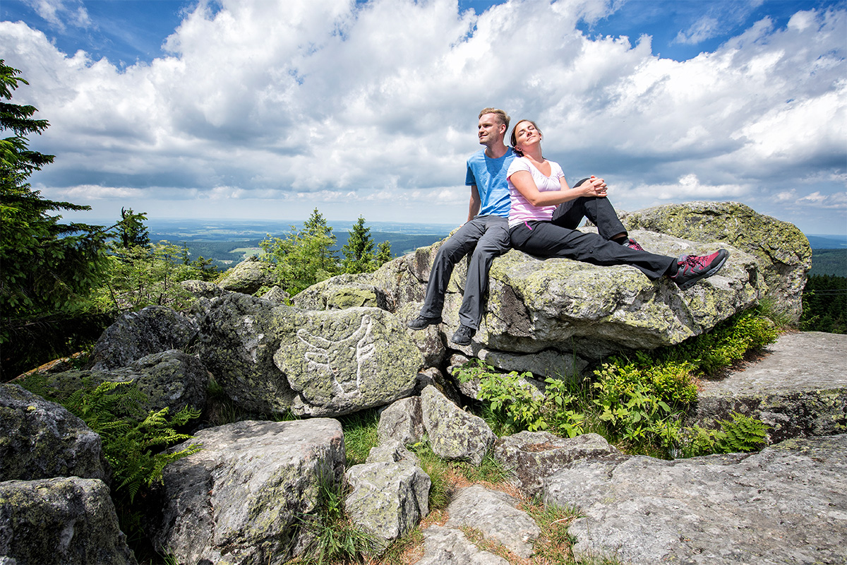 A couple sitting on a rock at the top of a mountain