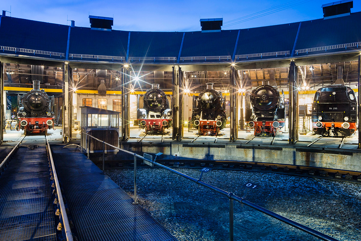 Dampflokomotiven im Lokschuppen mit geöffneten Toren am Abend