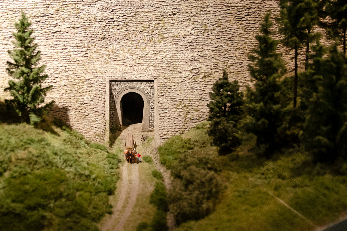 Scenery of the model railway with a horse carriage in front of a stone wall