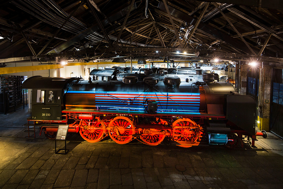 A locomotive is illuminated by a projector inside the engine shed