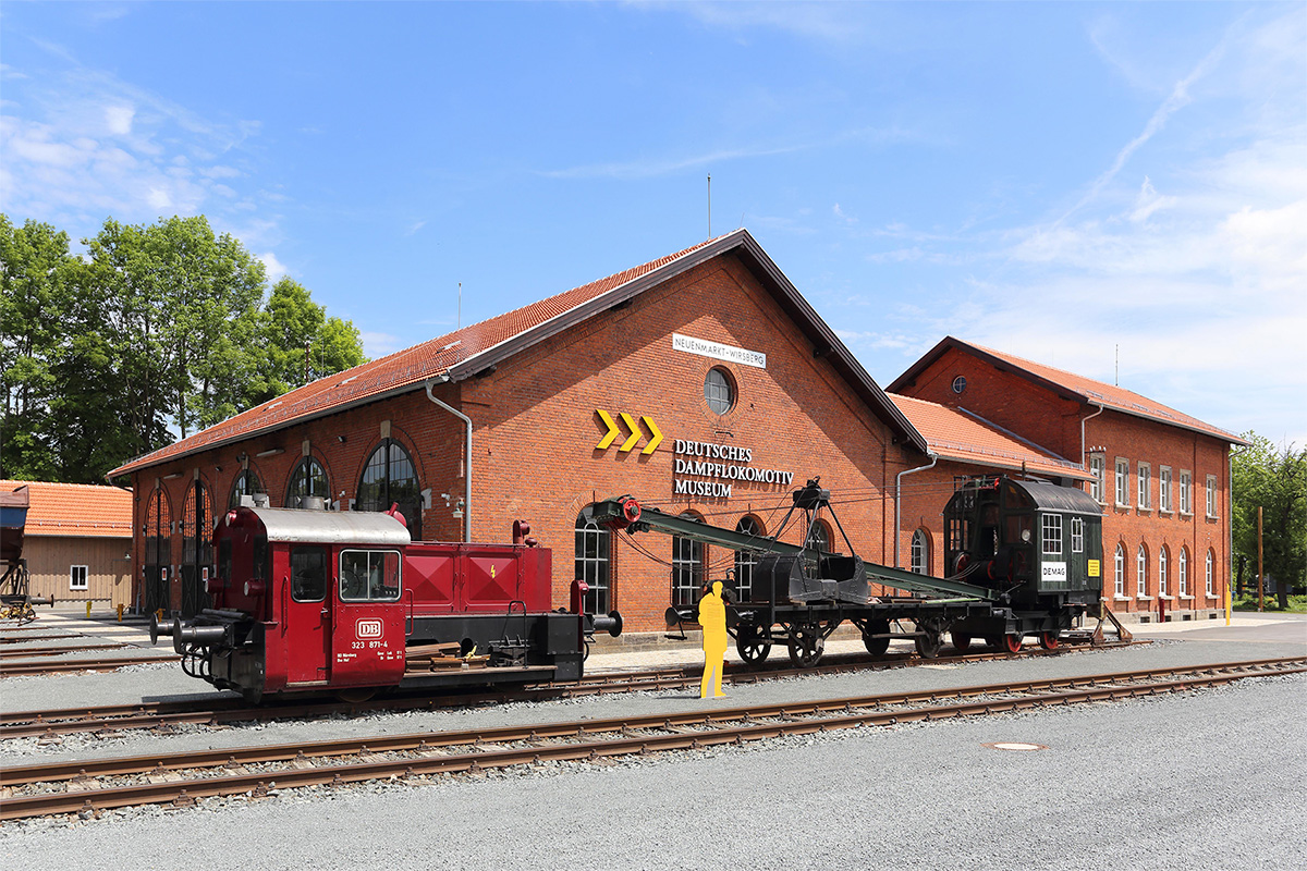 Outdoor area with the engine shed and a diesel locomotive as well as the DEMAG steam crane