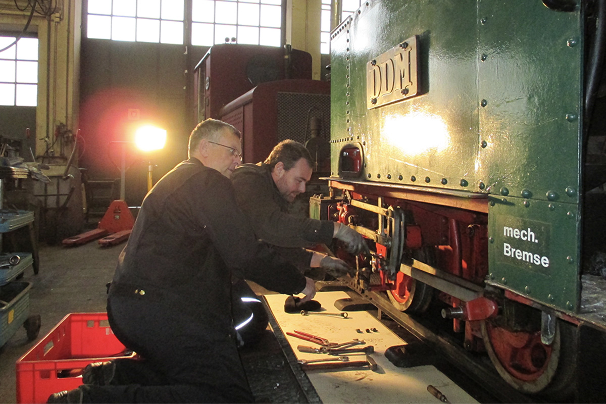 Two members of the friends' association are working on a locomotive